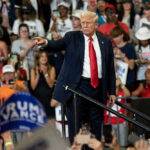 Man pointing in front of cheering crowd at rally.