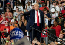 Iran Gamble Meets Cage Match Man pointing in front of cheering crowd at rally.