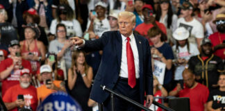 Man pointing in front of cheering crowd at rally.