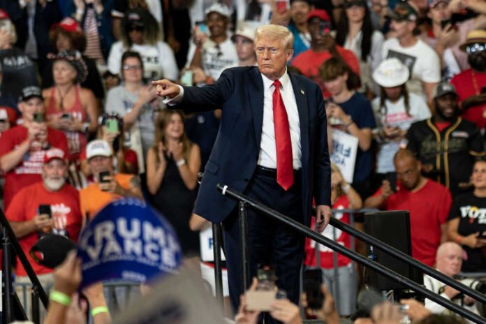 Man pointing in front of cheering crowd at rally.