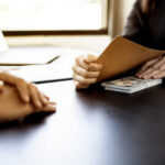 Two individuals in a professional setting exchanging documents