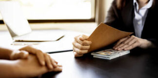 Two individuals in a professional setting exchanging documents
