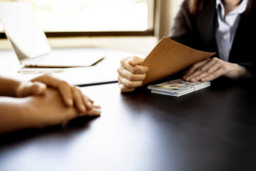 Two individuals in a professional setting exchanging documents