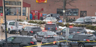 Multiple police vehicles at a scene with caution tape and emergency lights activated