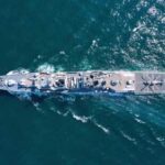 Aerial view of a naval ship navigating through the ocean