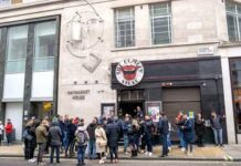 A crowd of people waiting outside a restaurant in an urban area