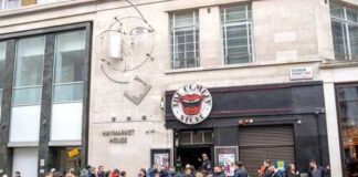 A crowd of people waiting outside a restaurant in an urban area