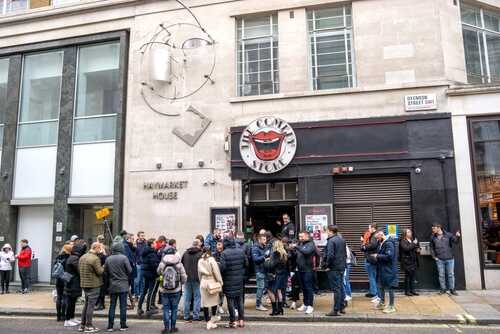 A crowd of people waiting outside a restaurant in an urban area