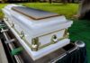 Insurance Dad’s Chilling Confession A white coffin placed on a green cloth at a cemetery
