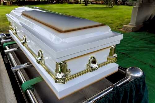 During,Funeral,Memorial,Service,,Coffin,Is,With,Deceased A white coffin placed on a green cloth at a cemetery