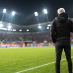 Soccer coach observing the game from the sidelines at night