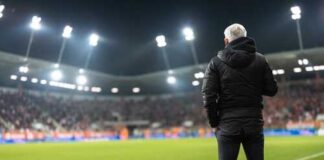 Soccer coach observing the game from the sidelines at night