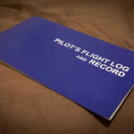 Night Takeoff, Fiery Dive, Family Dies Blue pilots flight log and record book on table