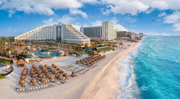 1956007453 Beachfront resort with sand chairs and turquoise ocean water