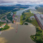 Aerial view of the Panama Canal with ships and surrounding landscape