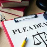 Document titled 'PLEA DEAL' with a gavel and legal books in the background