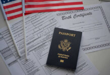 A U.S. passport, birth certificate, and American flags on a table