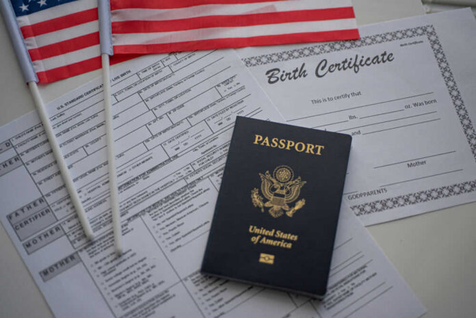1631039308 A U.S. passport, birth certificate, and American flags on a table