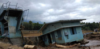 A collapsed building and debris in a muddy area after a flood