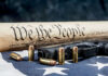 Illegal Pistols Fuel America’s Killing Machine? Constitution text bullets handgun and American flag