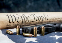 Constitution text bullets handgun and American flag