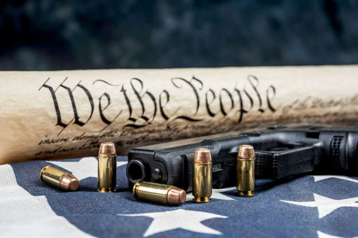1864724608 Constitution text bullets handgun and American flag