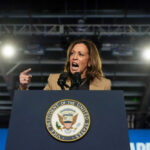 Person speaking passionately at a podium with microphones.
