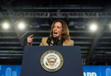 Person speaking passionately at a podium with microphones.