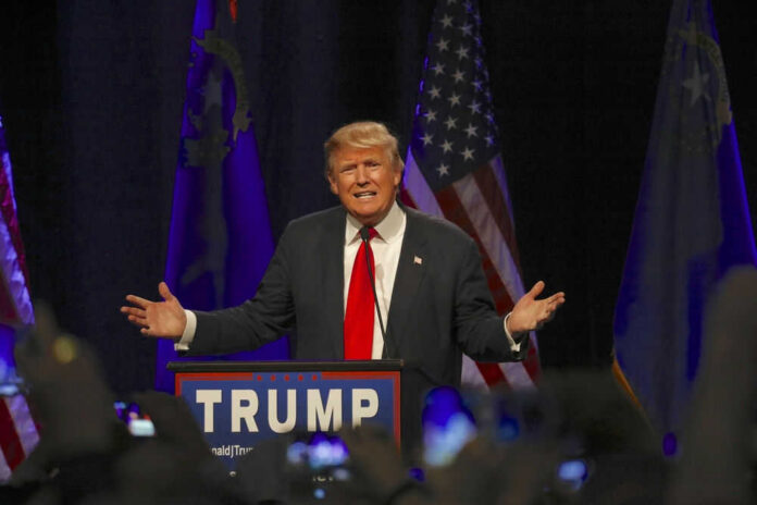 Man speaking at a podium with American flags.