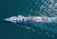 Aerial view of a naval ship navigating through the ocean