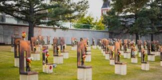 A memorial site with numerous sculptures and flowers in a grassy area