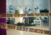 Police crime scene tape blocking an area with investigators in the background