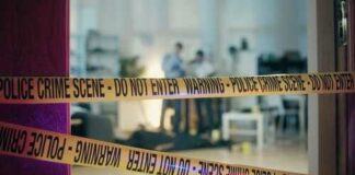 Police crime scene tape blocking an area with investigators in the background