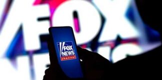A person holding a smartphone displaying the Fox News logo against a colorful background