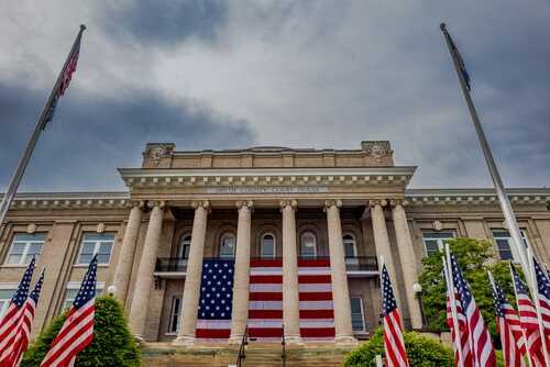 Historic building with large American flag and multiple flags in front