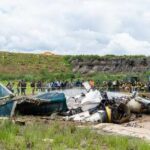 Wreckage of a crashed airplane with emergency responders and onlookers