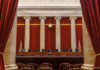 Interior view of a courtroom with red curtains and marble columns