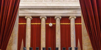 Interior view of a courtroom with red curtains and marble columns