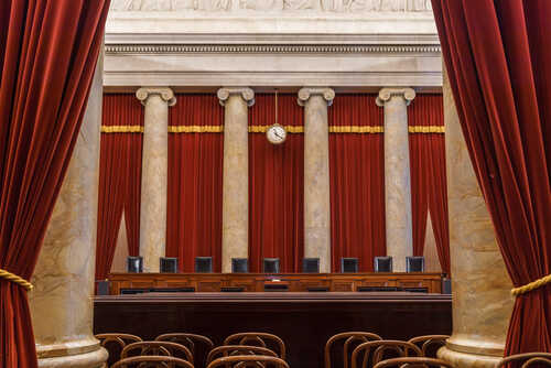 Interior view of a courtroom with red curtains and marble columns