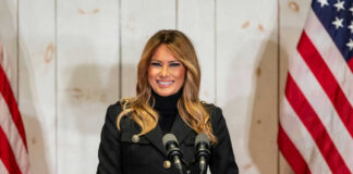Woman speaking at podium with American flags.