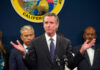 Man speaking at podium with people behind him