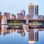 NYC Bleeds Gen Z’s, Where Are They Going? City skyline and bridge reflecting on calm water