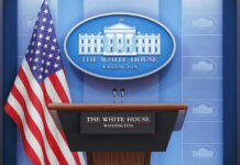 Trump Boots CNN – Court Fight Explodes Podium with microphones in front of American flag