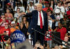 Man pointing in front of cheering crowd at rally.