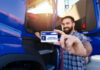 Deadly Crashes Spur ICE Crackdown Man holding a commercial driver's license in front of a blue truck