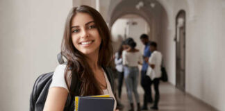 Smiling student holding books in a school hallway
