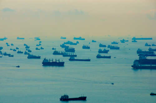 Numerous cargo ships scattered across a hazy ocean
