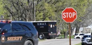 A sheriff's vehicle and a SWAT truck near a stop sign on a road